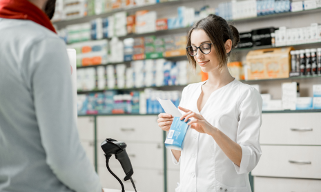 Mitarbeiterin misst den Blutdruck einer Kundin in einer Apotheke